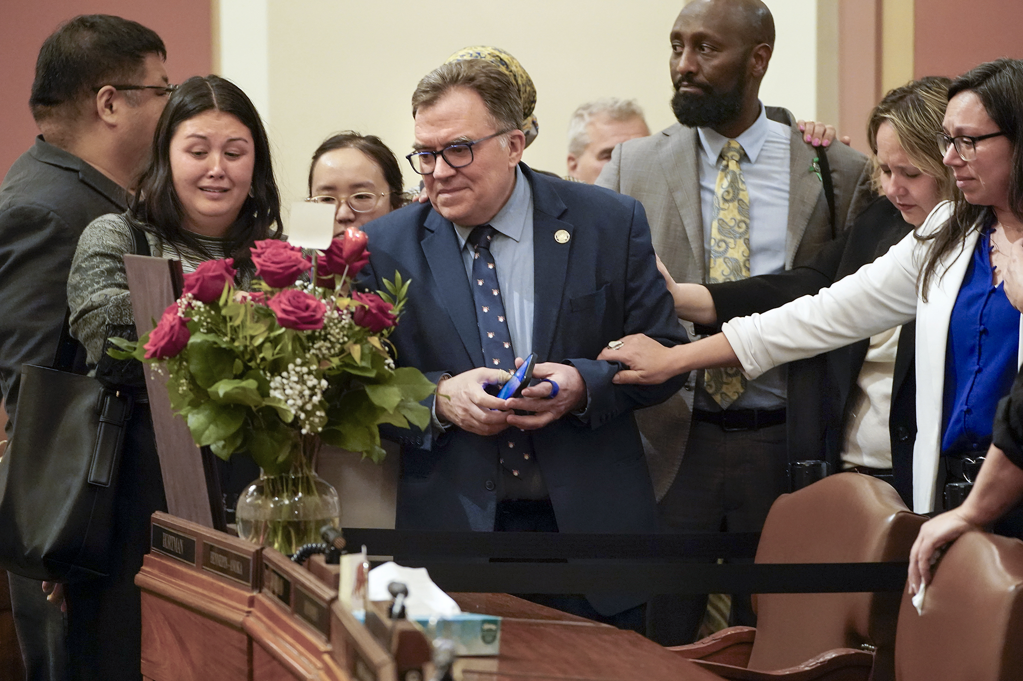 Surrounded by DFL House members, Sen. John Hoffman pays his respects to the late Speaker Emerita Melissa Hortman at her desk memorial following the end of Sunday's floor session. (Photo by Michele Jokinen)   